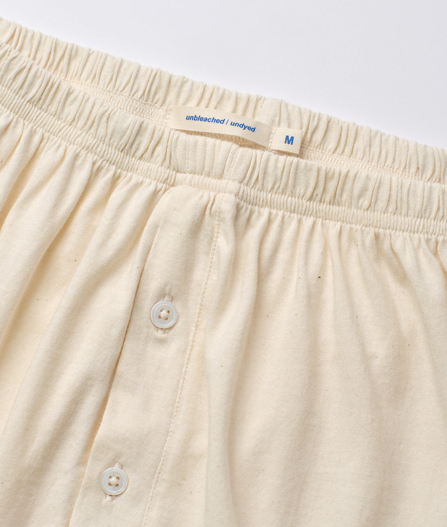 A close-up detail shot of a pair of unbleached and undyed cotton shorts with a size M label - Industry of All Nations