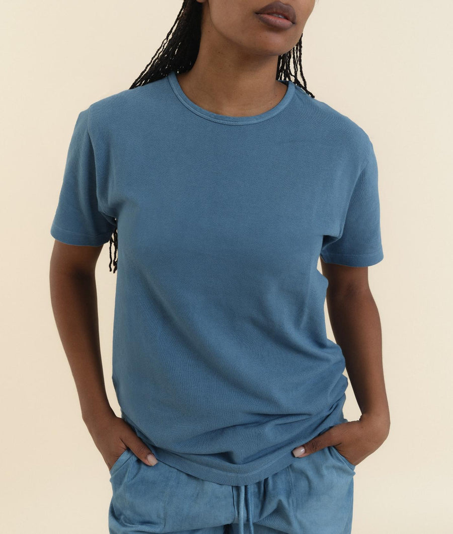 Close-up shot of a person wearing a blue cotton t-shirt from Industry of All Nations.