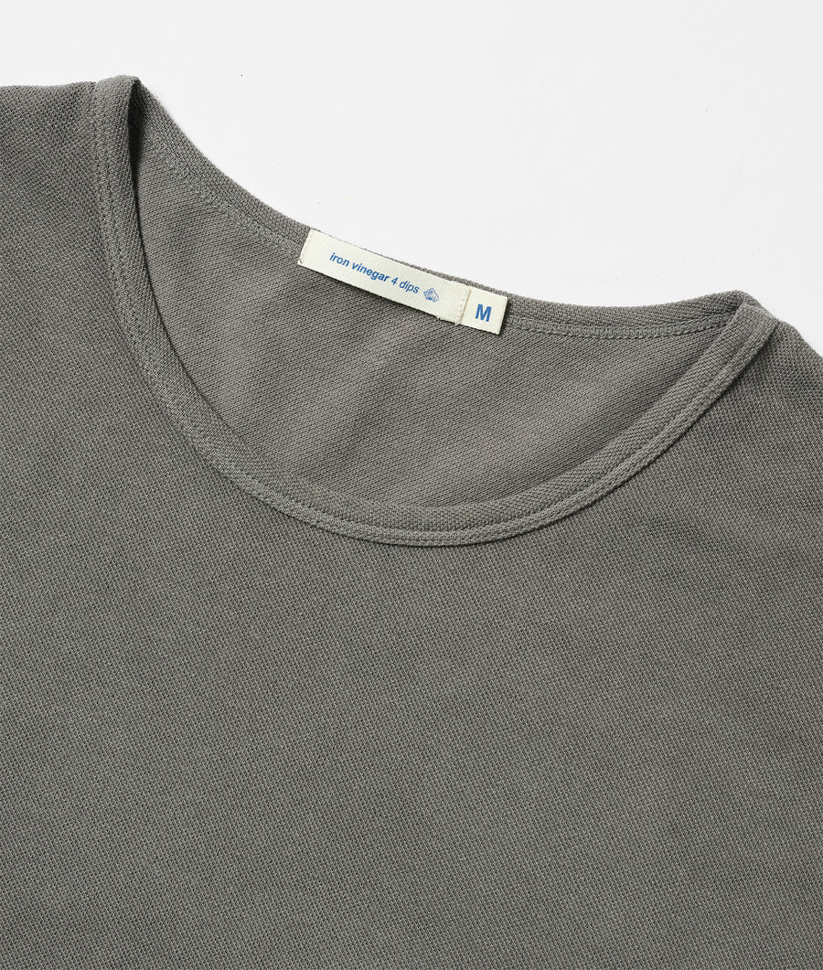 A close-up of a medium-sized grey knit t-shirt with a small brand tag - Industry of All Nations