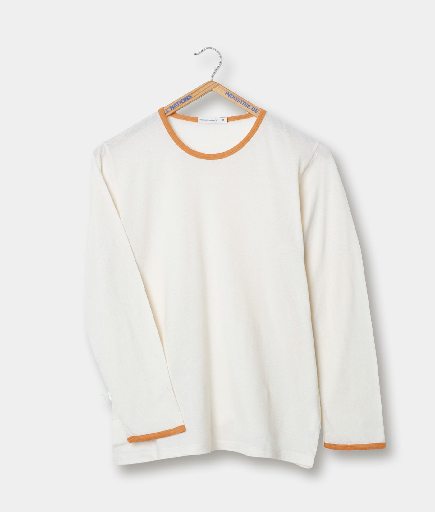 White long sleeve t-shirt with orange trim on a hanger against a light background