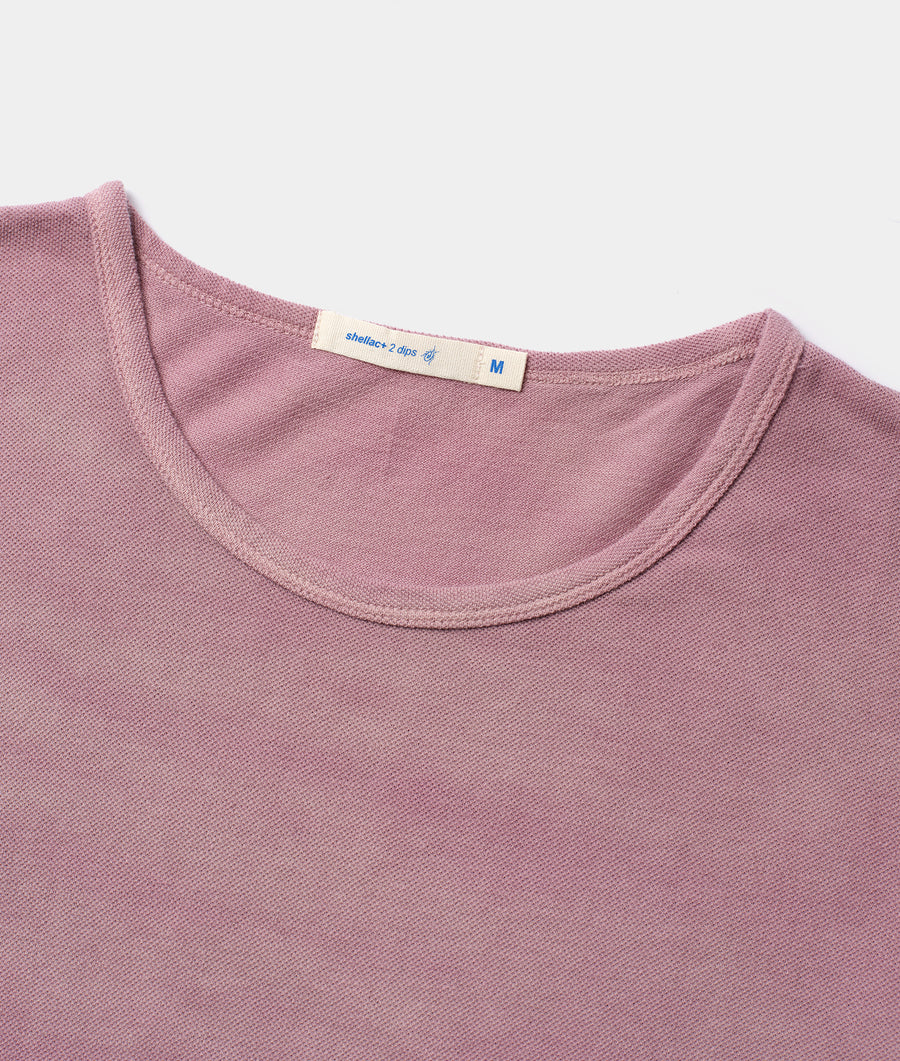 A close-up view of a pink cotton t-shirt with a size tag attached - Industry of All Nations
