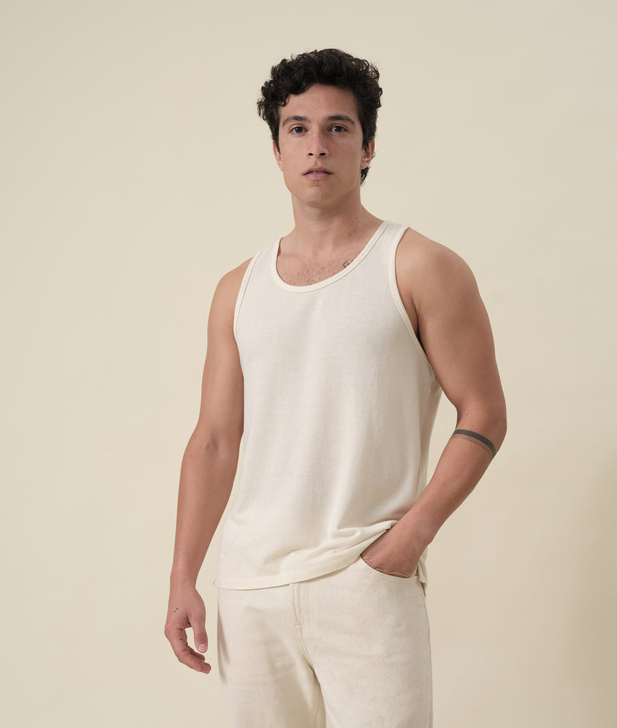 Portrait of a male model wearing a white tank top from the Industry of All Nations sustainable apparel brand.