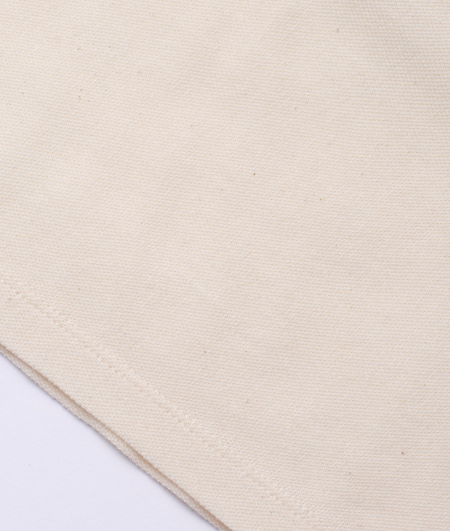 Flat lay image of a plain, off-white organic cotton fabric swatch - Industry of All Nations