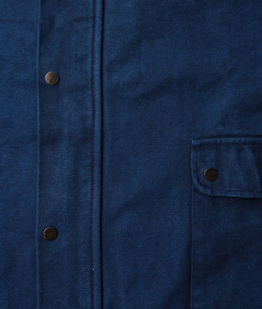 Dark blue organic cotton jacket with metal buttons, displayed in a close-up detail shot - Industry of All Nations