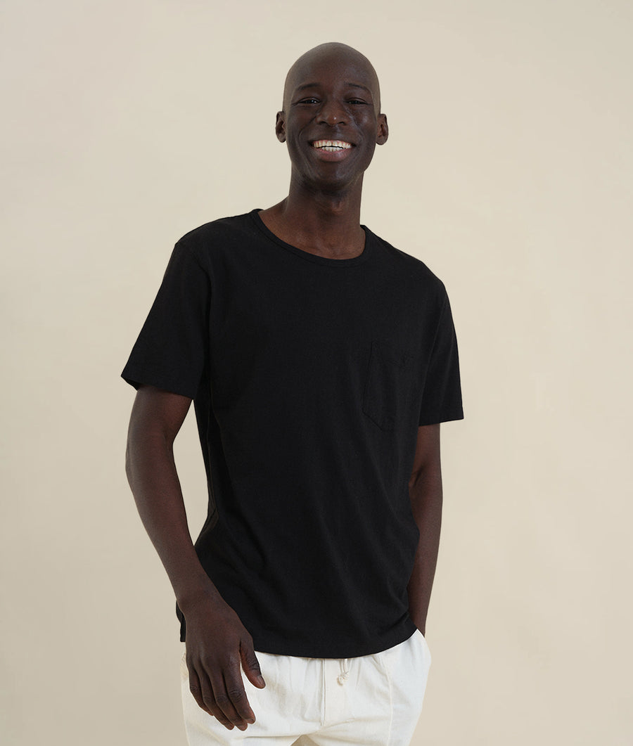 A smiling Black man wearing a black t-shirt - Industry of All Nations