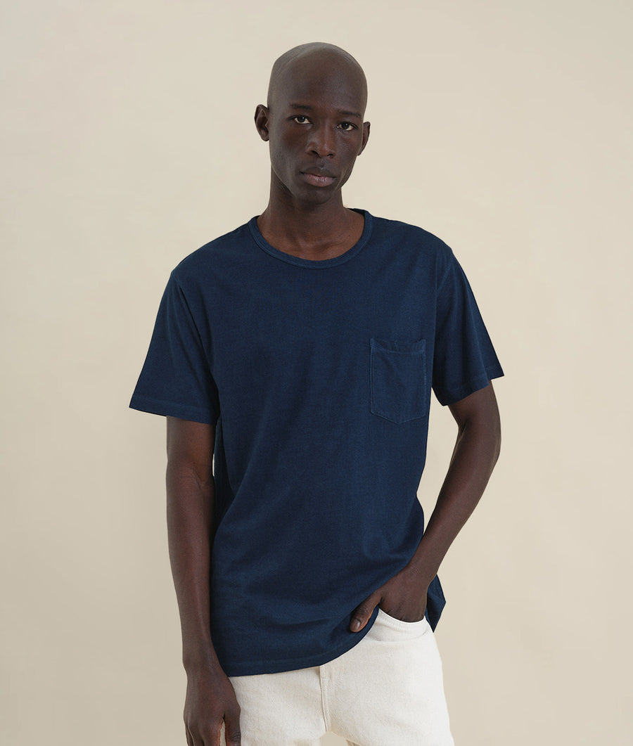 Navy blue t-shirt worn by a bald, Black male model standing against a neutral background - Industry of All Nations