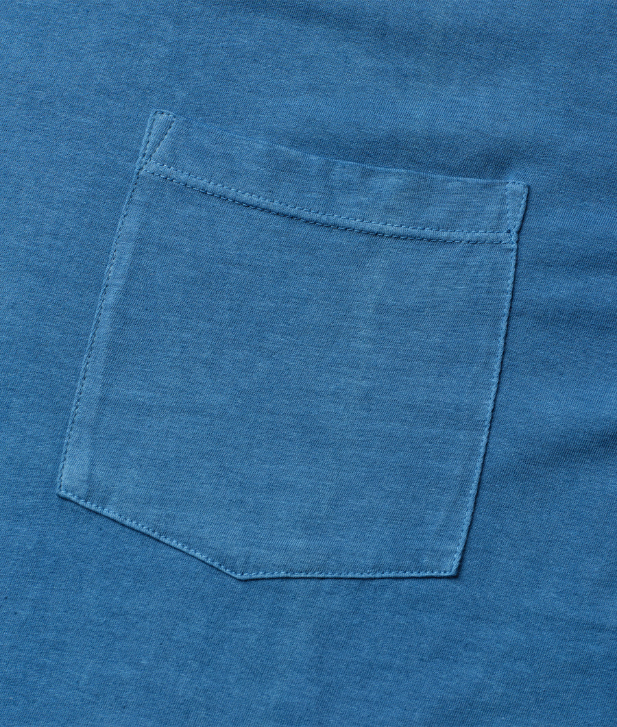 A close-up detail shot of a blue organic cotton t-shirt with a single chest pocket - Industry of All Nations