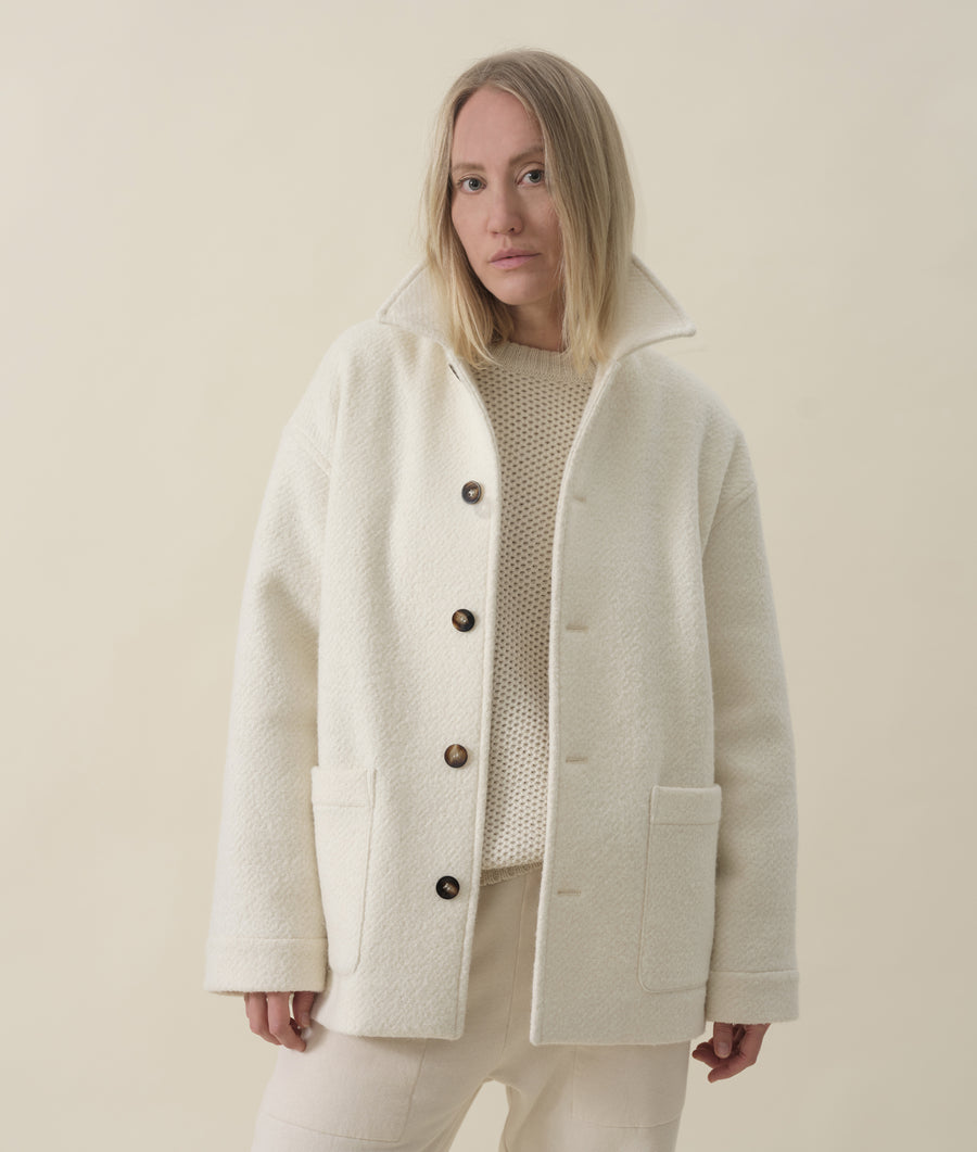 Portrait of a woman wearing a white wool coat with large buttons - Industry of All Nations