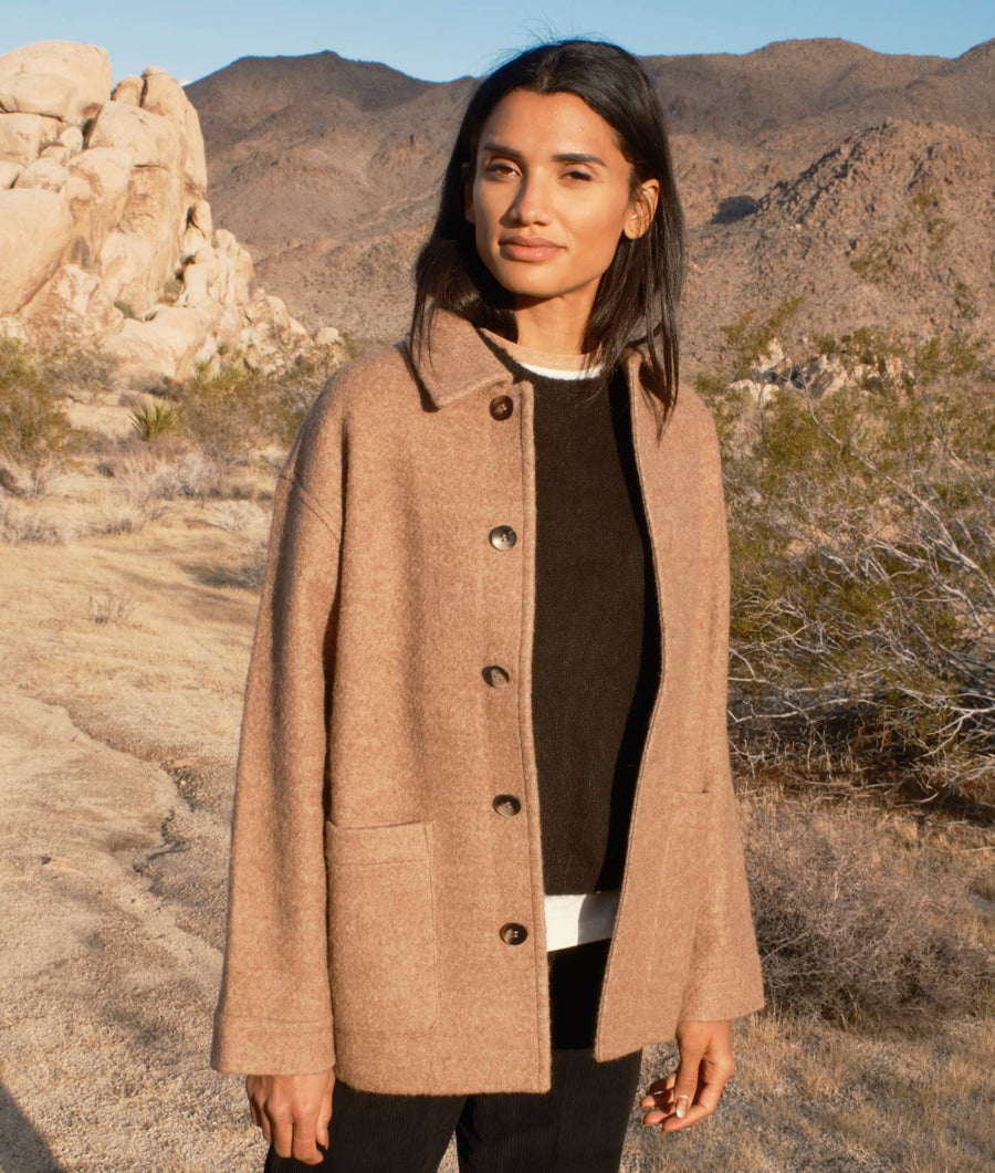 A woman wearing a beige wool coat in a desert landscape - Industry of All Nations