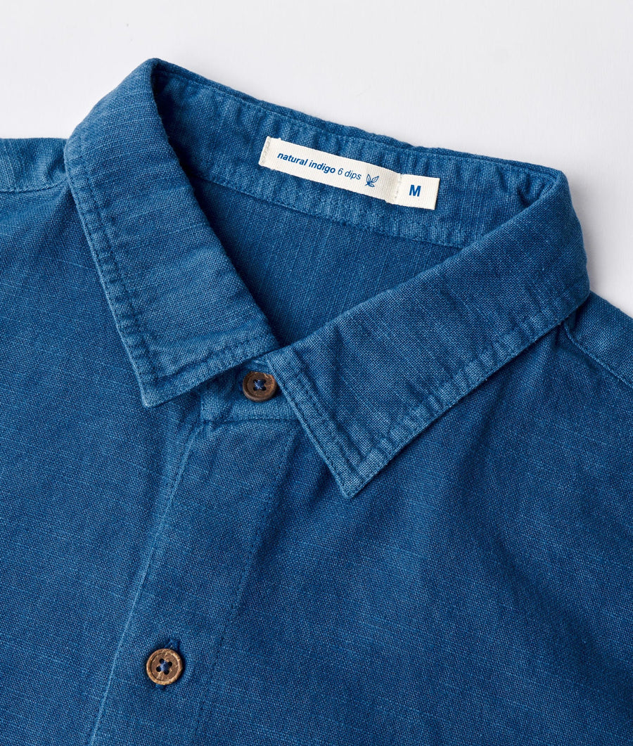 Close-up shot of a navy blue denim shirt with a label that says "natural indigo 6 dips" - Industry of All Nations