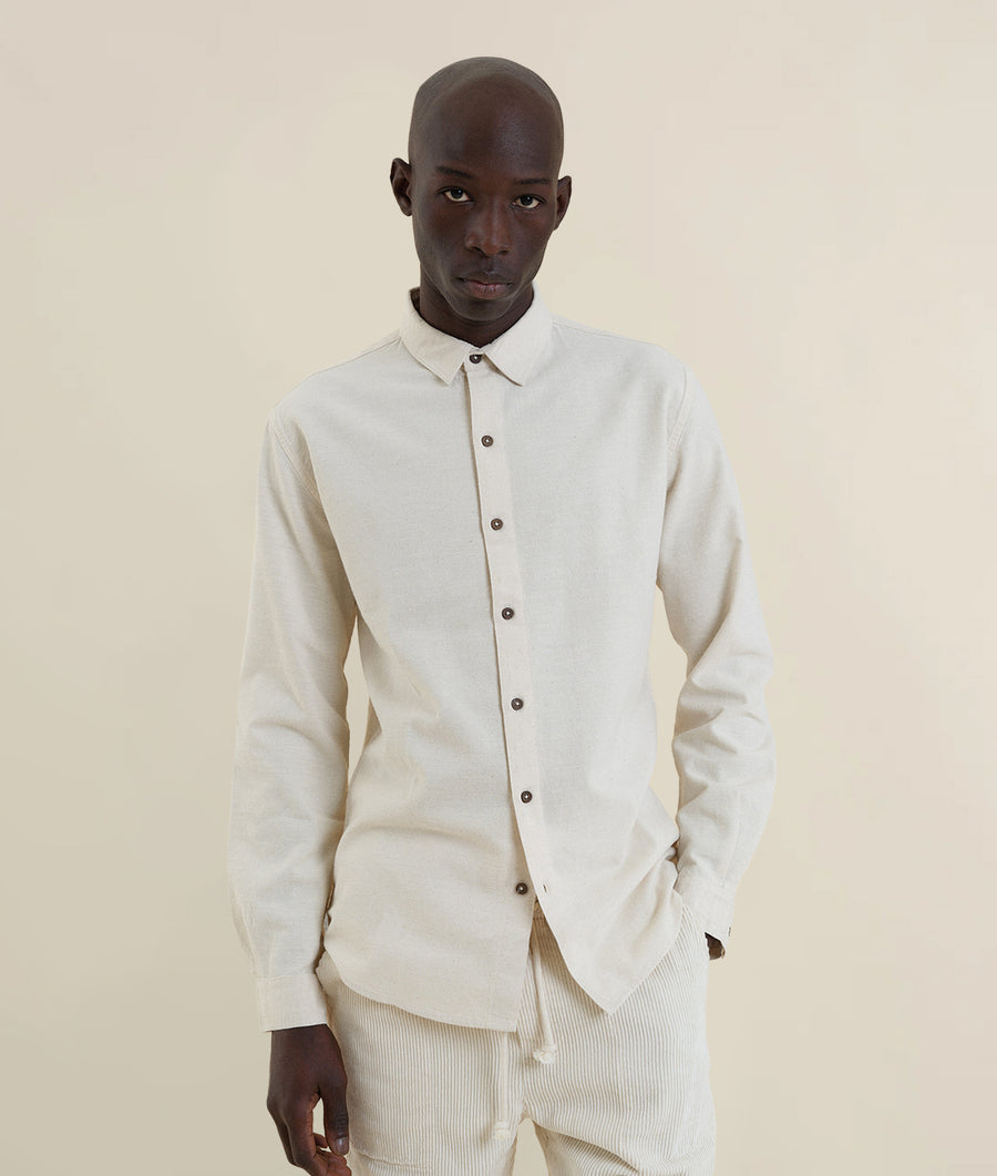A man wearing a white button-up shirt from Industry of All Nations.