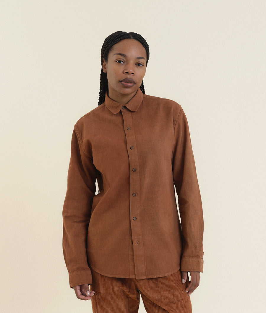 A woman wearing a rust-colored button-up shirt from Industry of All Nations