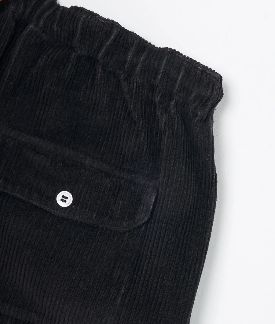 Detail shot of a black pleated skirt with a button detail - Industry of All Nations
