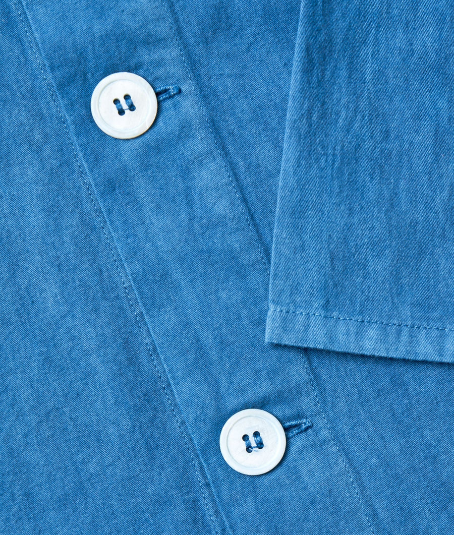 Detailed image of a blue denim jacket, flat lay with focus on the buttons - Industry of All Nations