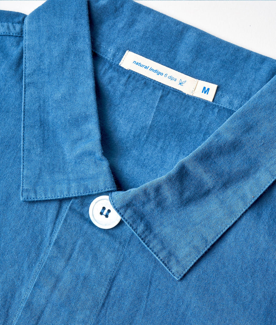 A close-up shot of a navy blue denim button-down shirt with a "natural indigo 6 dips" label - Industry of All Nations