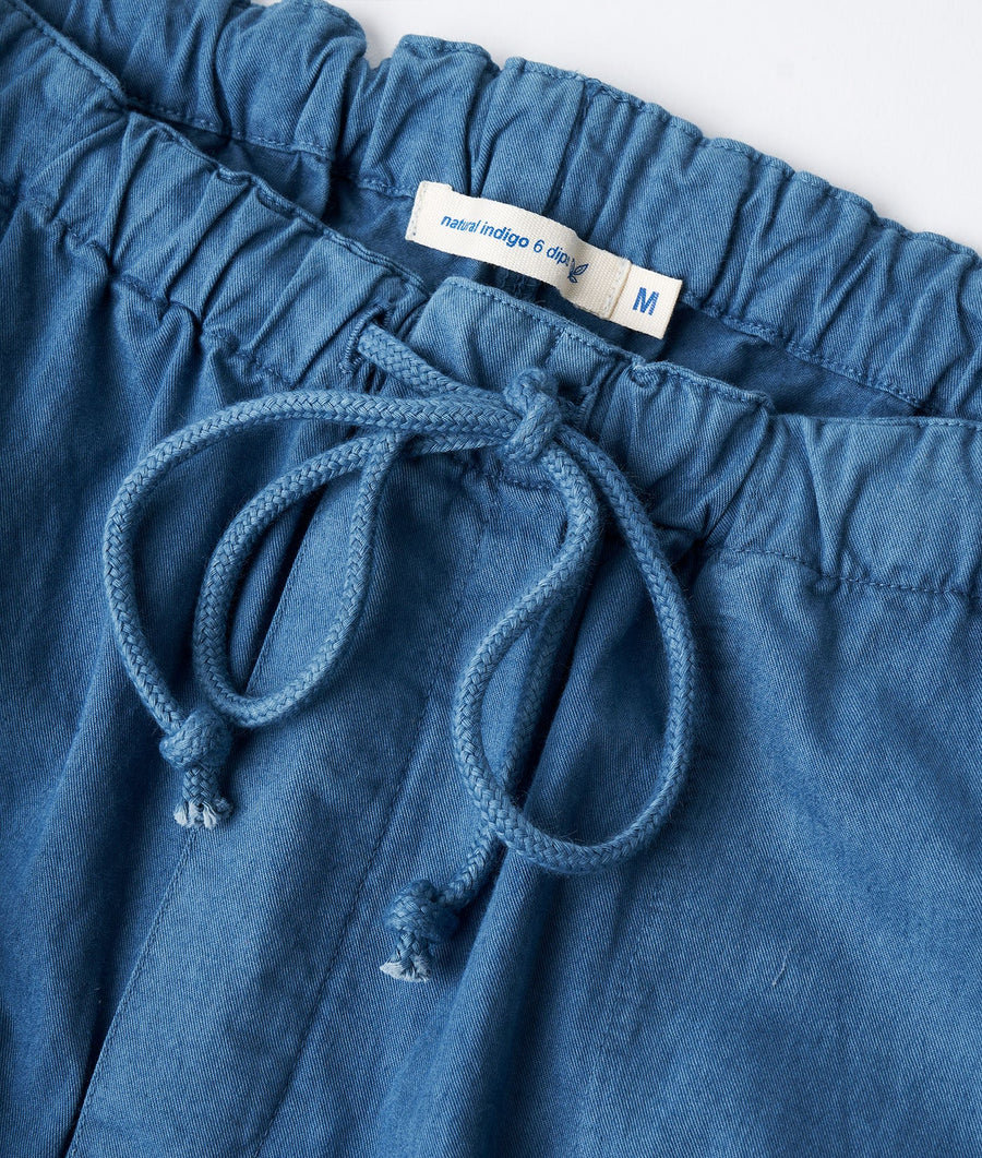 A close-up shot of a pair of medium-sized denim shorts with a drawstring waist and a 'Natural Indigo 6 days' label - Industry of All Nations.