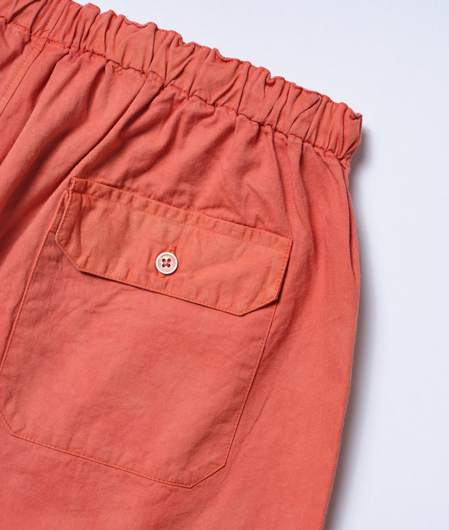 Ruched waist and large front pocket details on coral red cotton shorts, laid flat - Industry of All Nations