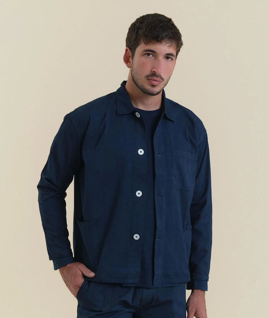 A man wearing a navy blue button-down jacket, standing against a plain background - Industry of All Nations