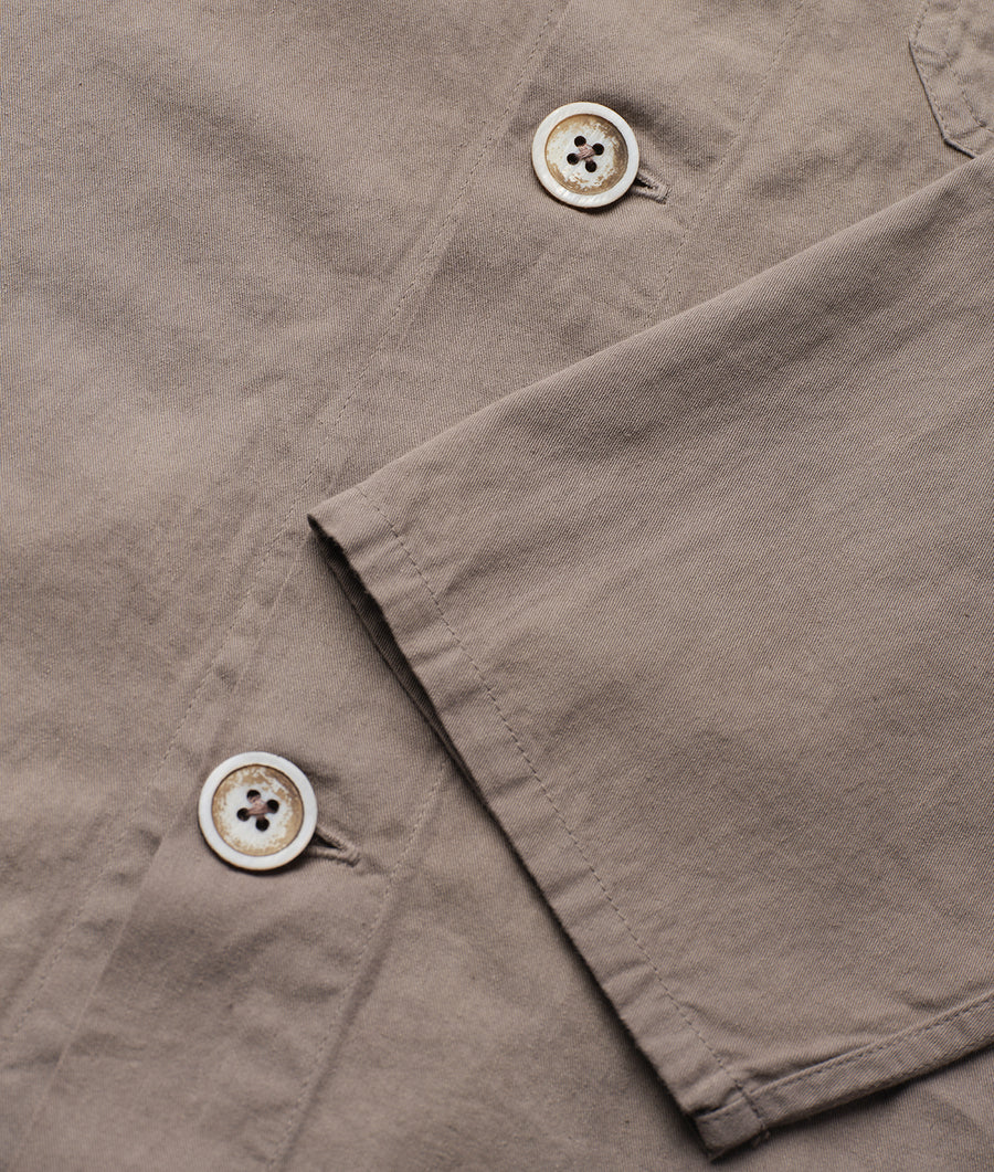 A close-up detail shot of two white buttons on a beige cotton garment from Industry of All Nations.