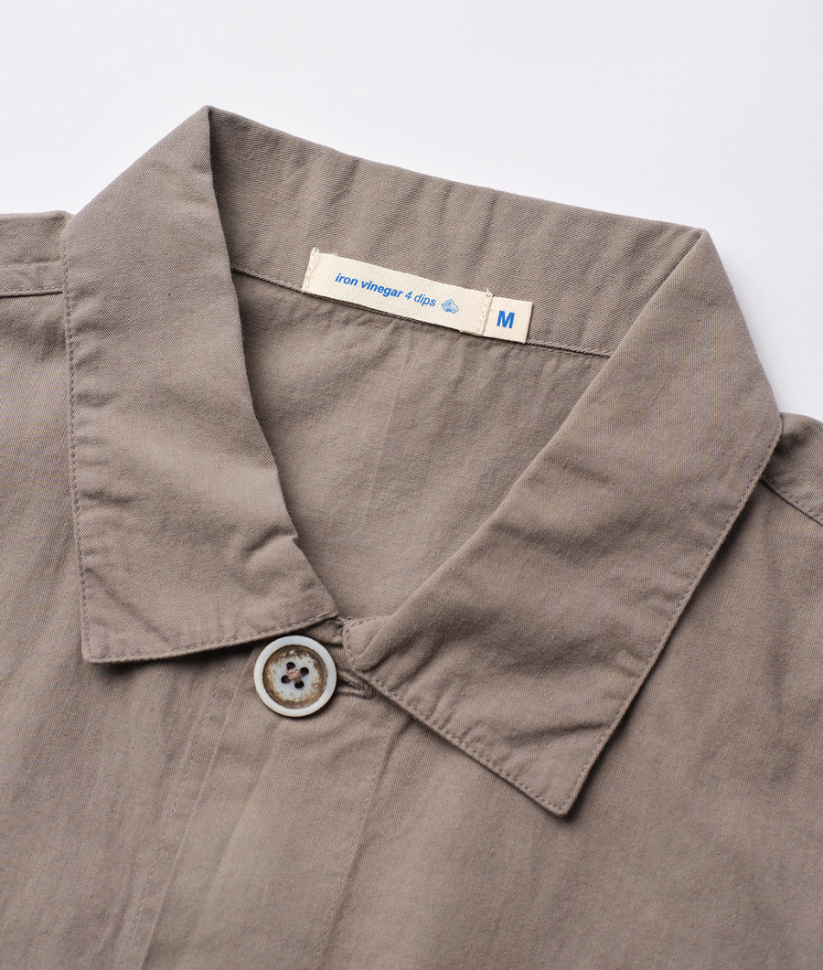 A close-up detail shot of a gray cotton shirt with a size M label from Industry of All Nations.