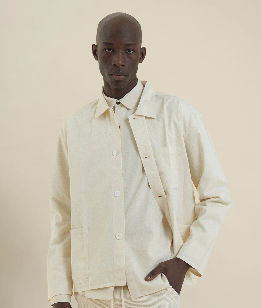 A man wearing a white cotton jacket with a collar and pockets - Industry of All Nations