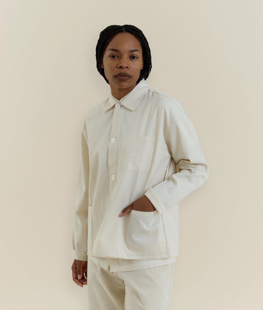 A person wearing a white organic cotton overshirt from Industry of All Nations.