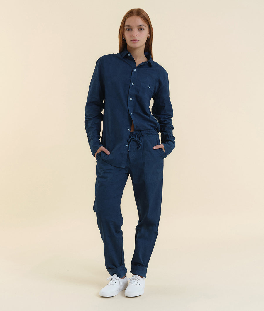 Navy blue button-down jumpsuit worn by a young woman with white sneakers - Industry of All Nations