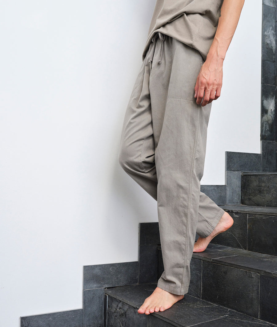 Beige cotton jumpsuit worn by model, standing on stairs with bare feet - Industry of All Nations