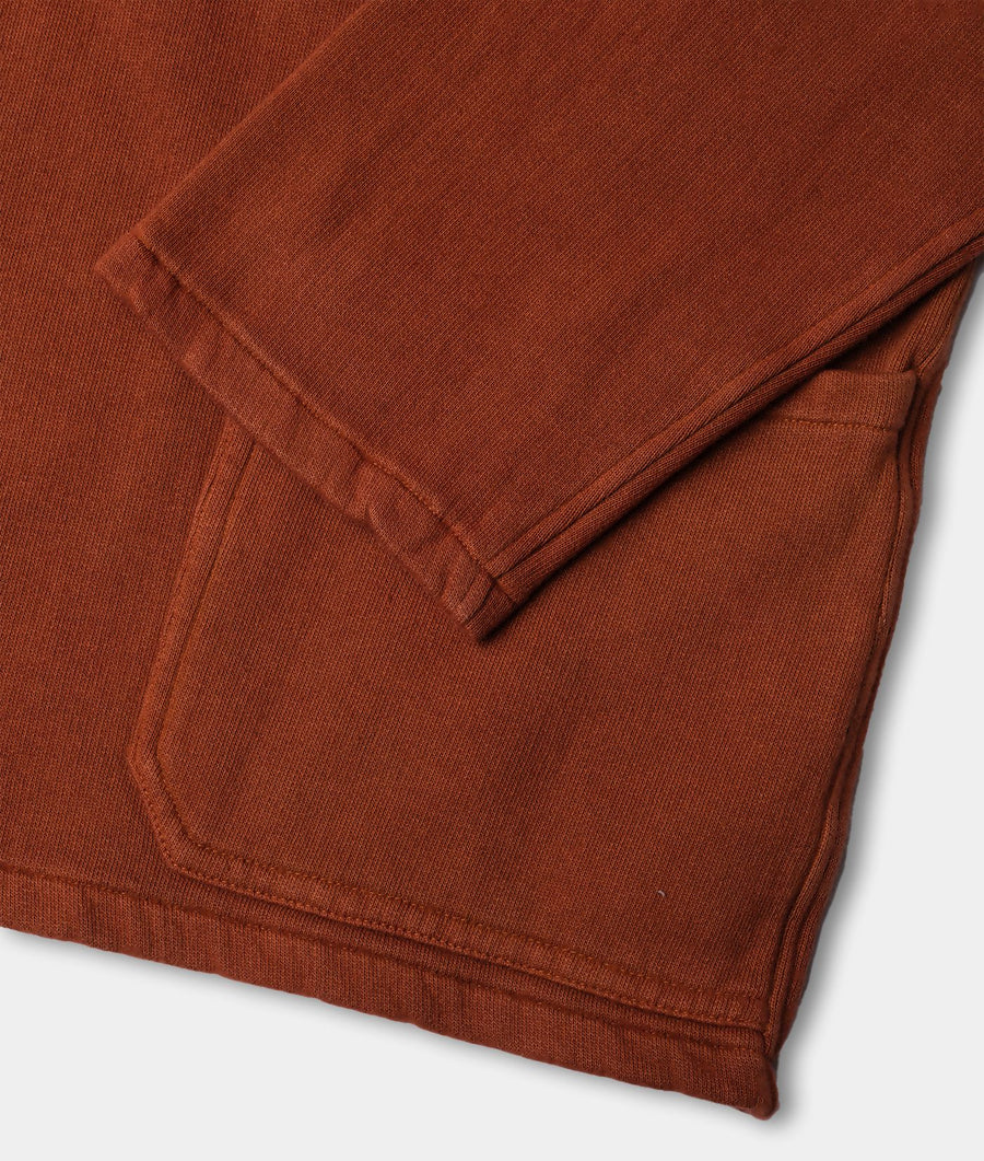 A close-up detail shot of a rust-colored, ribbed organic cotton crewneck sweater - Industry of All Nations