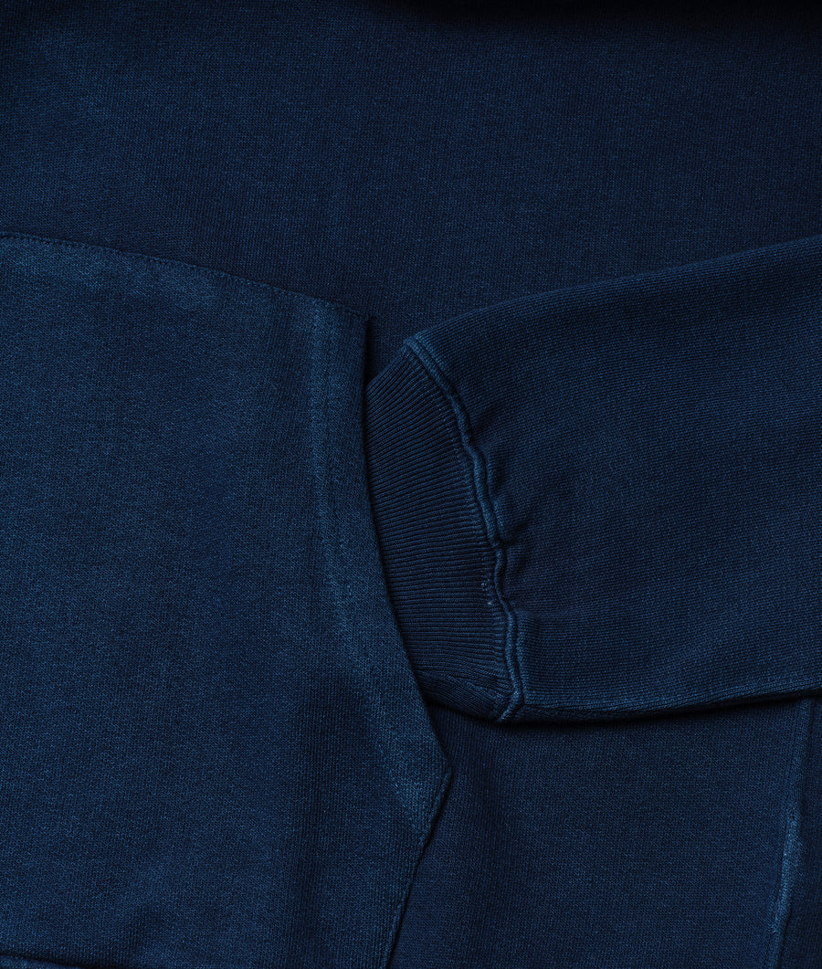 A close-up detail shot of a navy blue wool or cotton knit cardigan sweater with ribbed cuffs and collar - Industry of All Nations