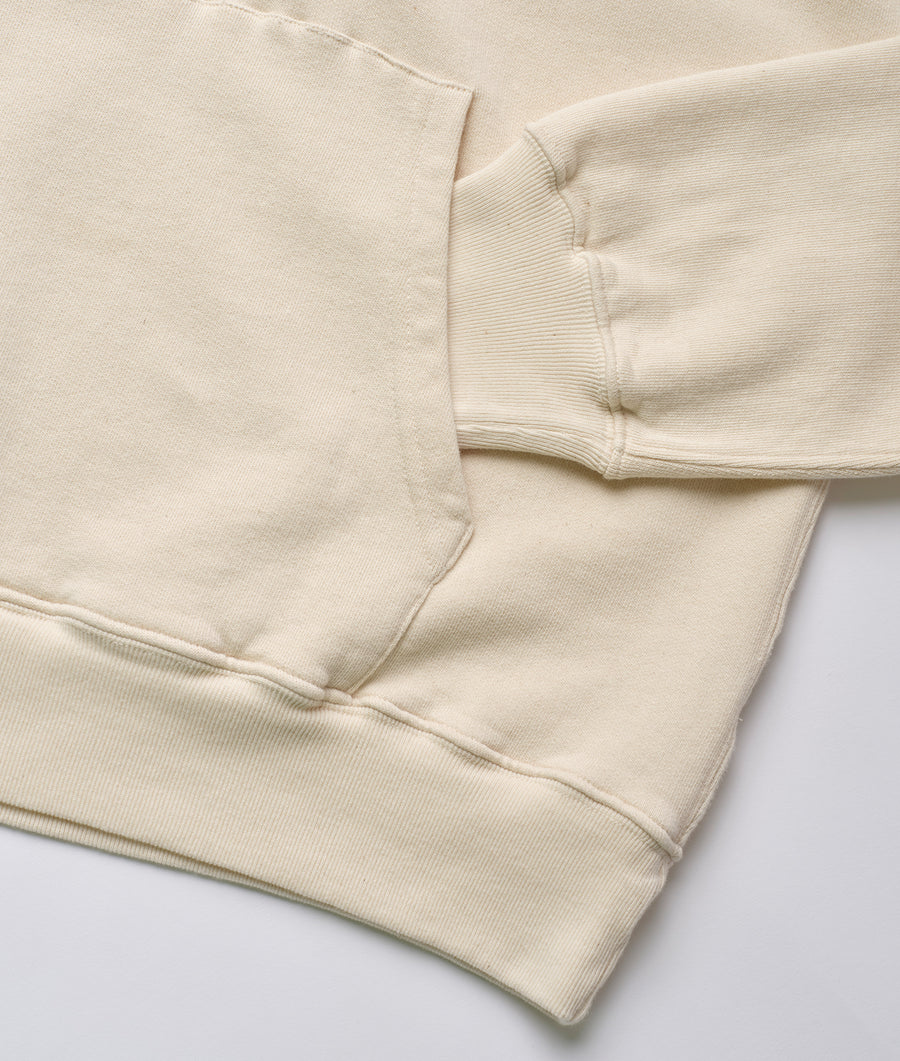 Closeup detail of a cream-colored organic cotton sweatshirt against a plain white background - Industry of All Nations