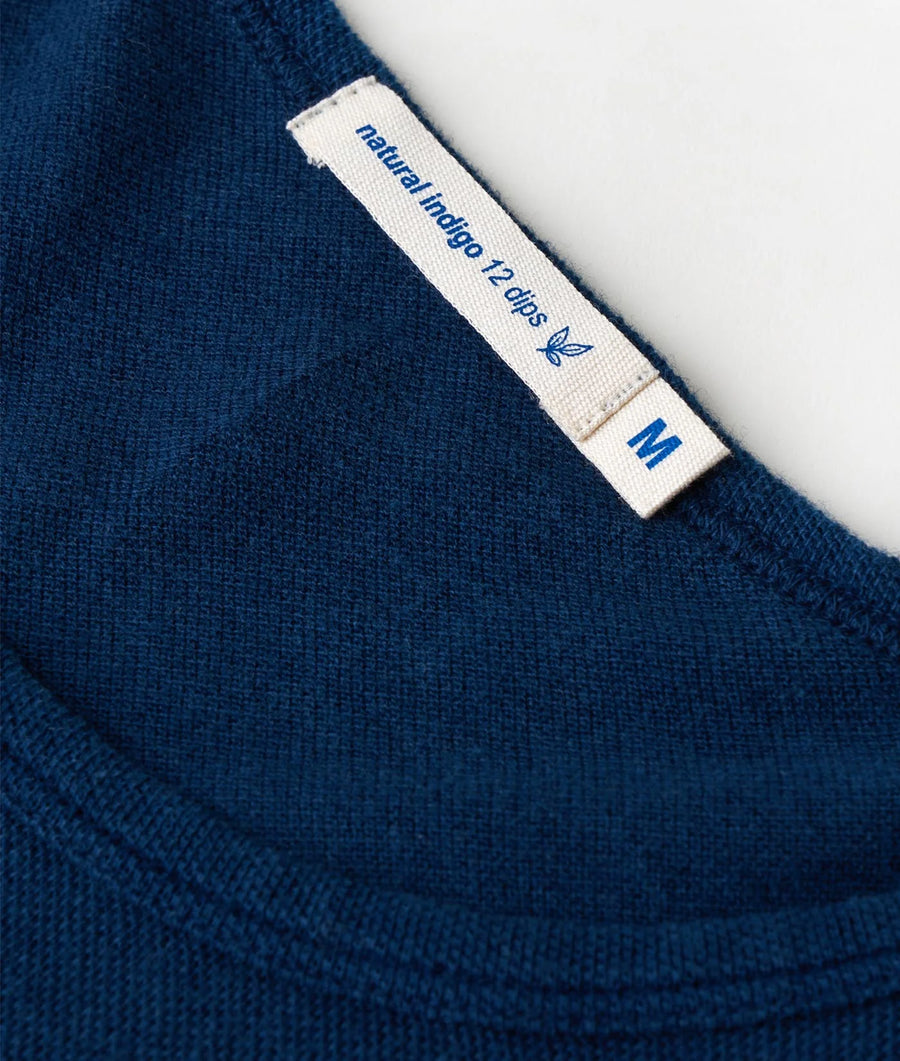 Closeup image of a navy blue organic cotton sweater with a woven label that reads 'Natural Indigo 12 days' - Industry of All Nations