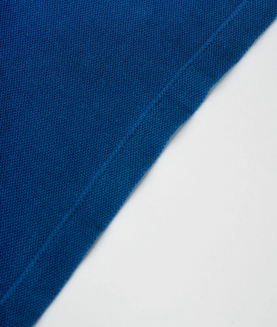 A close-up detail shot of a vibrant blue cotton fabric with a smooth, uniform texture - Industry of All Nations