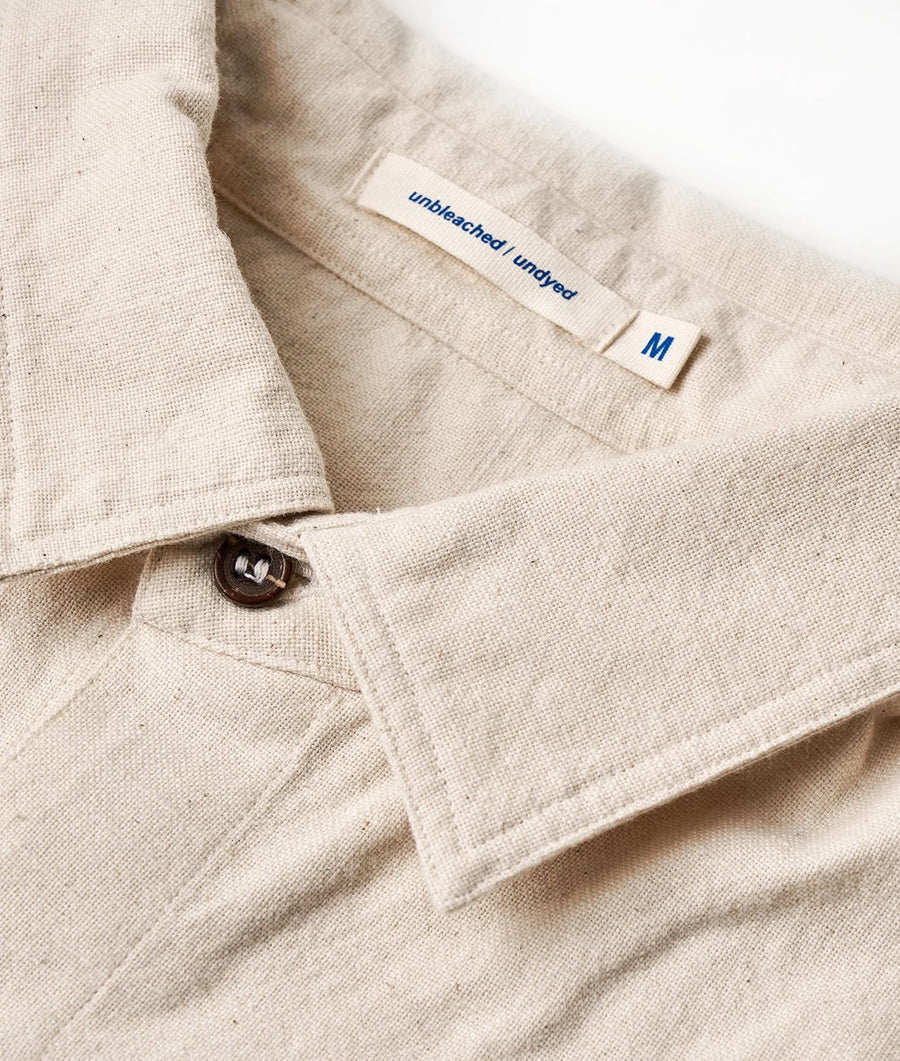 Detail shot of a medium-sized unbleached and undyed cotton garment with a sewn-on label - Industry of All Nations