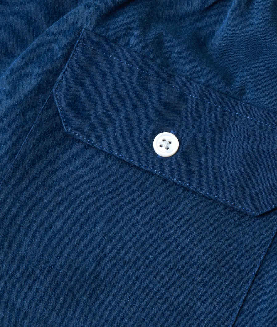 Detail shot of a navy blue cotton shirt pocket with a white button - Industry of All Nations
