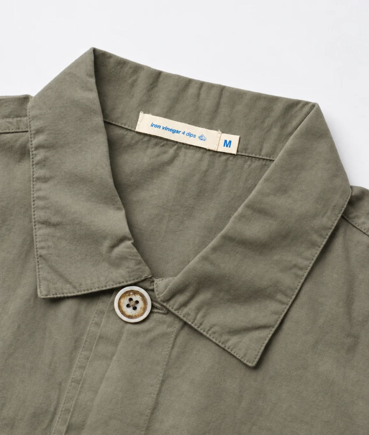 Close-up of an olive green collared shirt with a buttoned collar and a visible neck label reading 'love vintage a day M'.