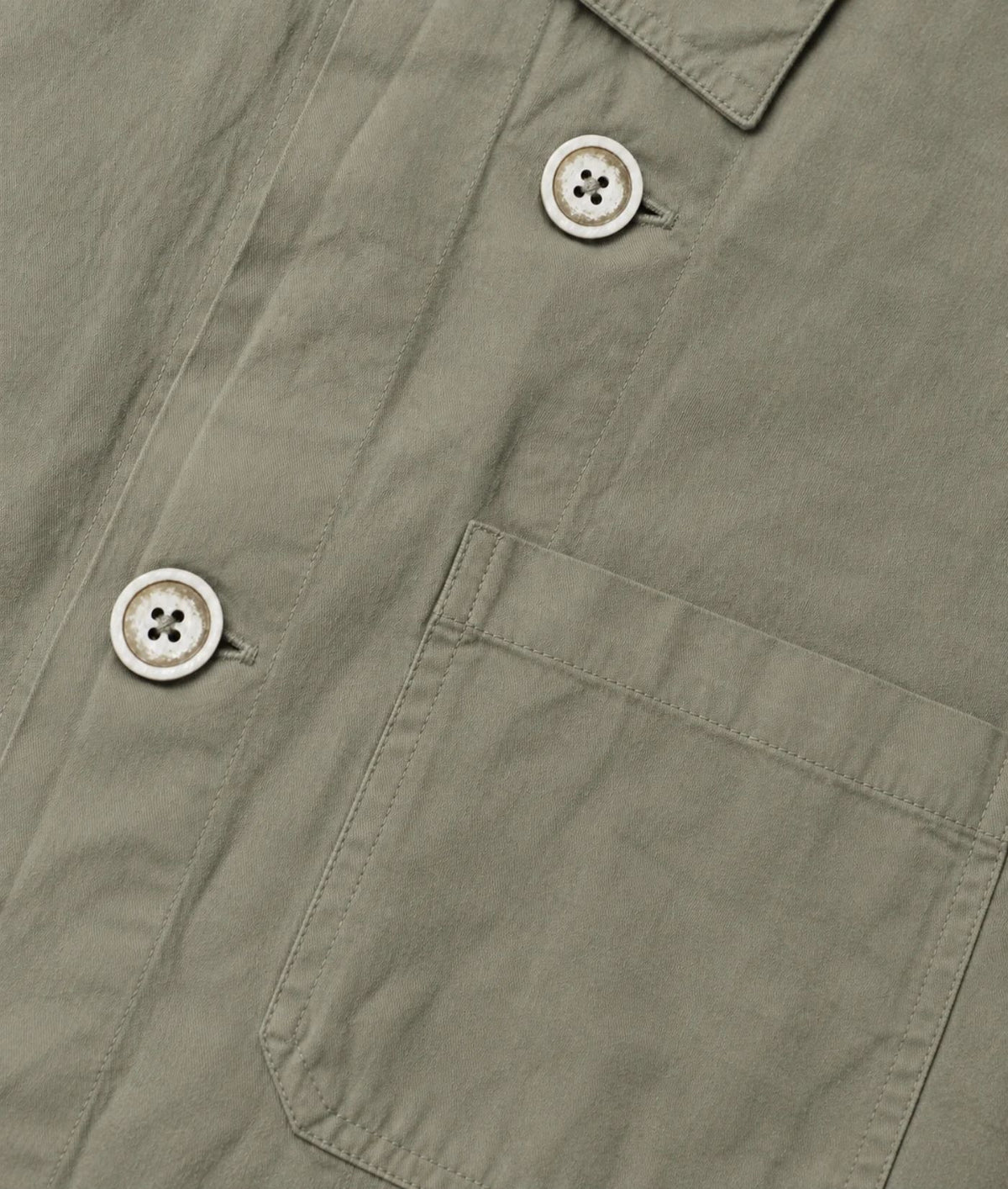 Close-up of an olive green shirt jacket showing a buttoned collar, front button placket, and a chest pocket.