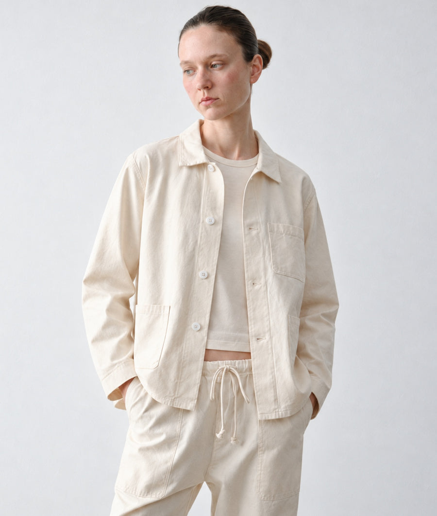A model wearing IOAN undyed Ponya jacket over a matching crewneck shirt and drawstring trousers, photographed against a neutral light gray studio background.