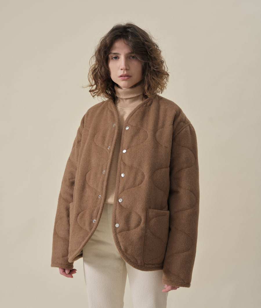 The model is wearing a brown fuzzy textured button-up jacket with a high collar - Industry of All Nations