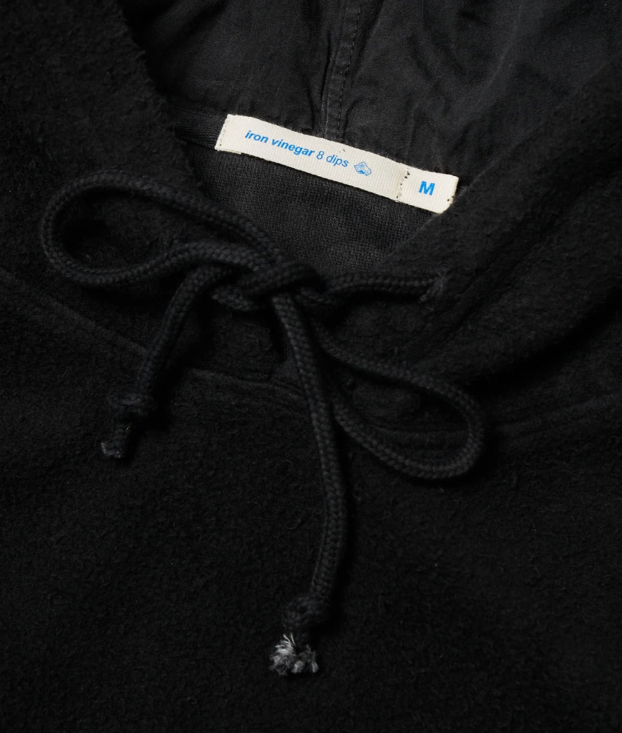 Detail shot of a black cotton garment with an "Iron vinegar 8 clips" clothing tag - Industry of All Nations