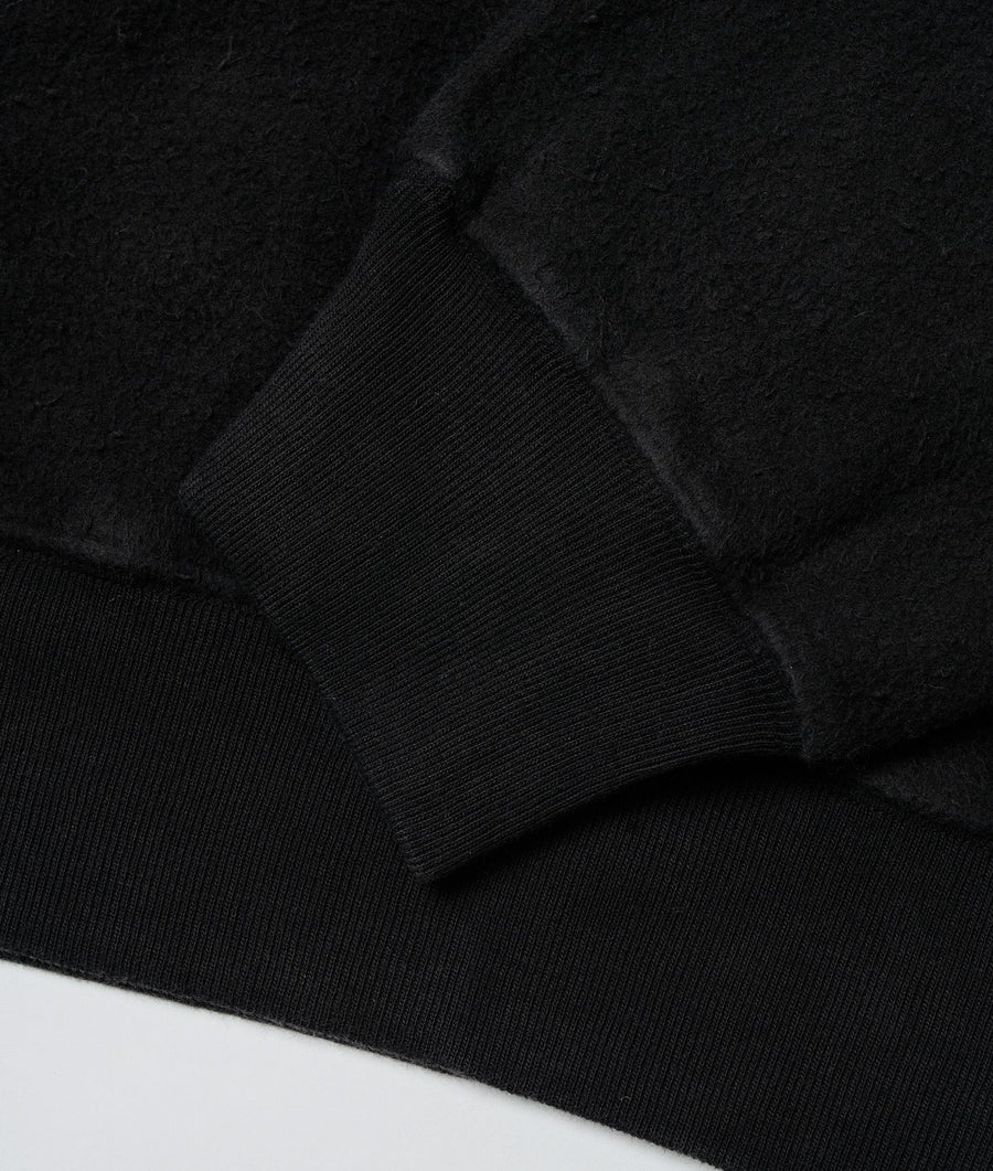 Black ribbed knit sweater or pullover, folded on a dark surface - Industry of All Nations