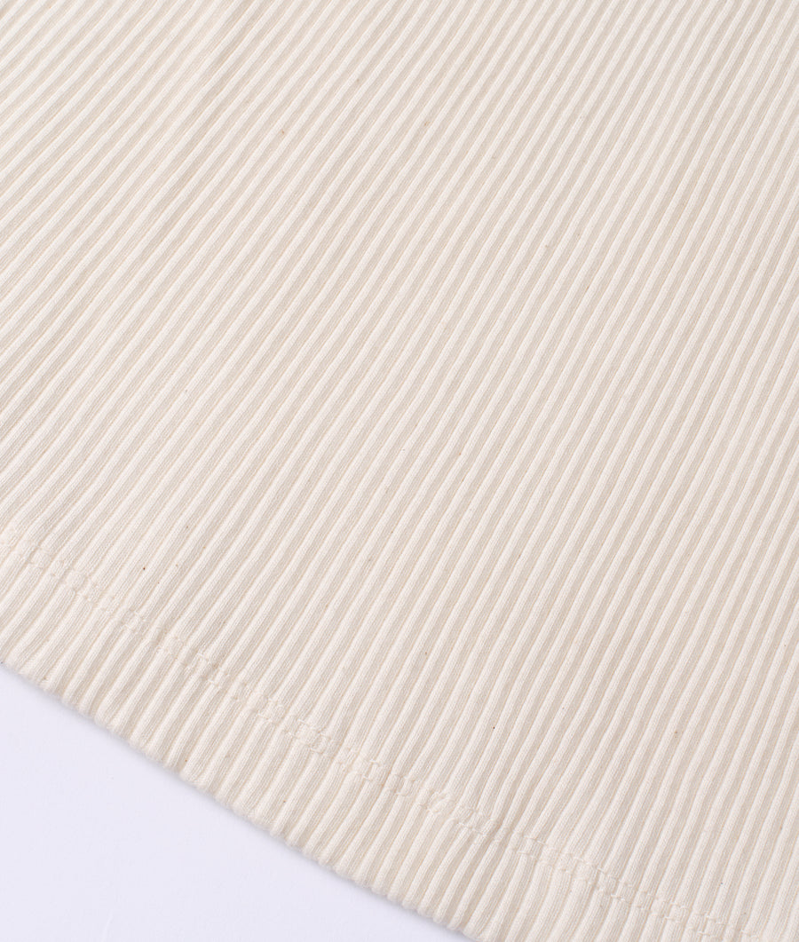 Flat lay image of a cream-colored cotton garment with diagonal stripe pattern - Industry of All Nations