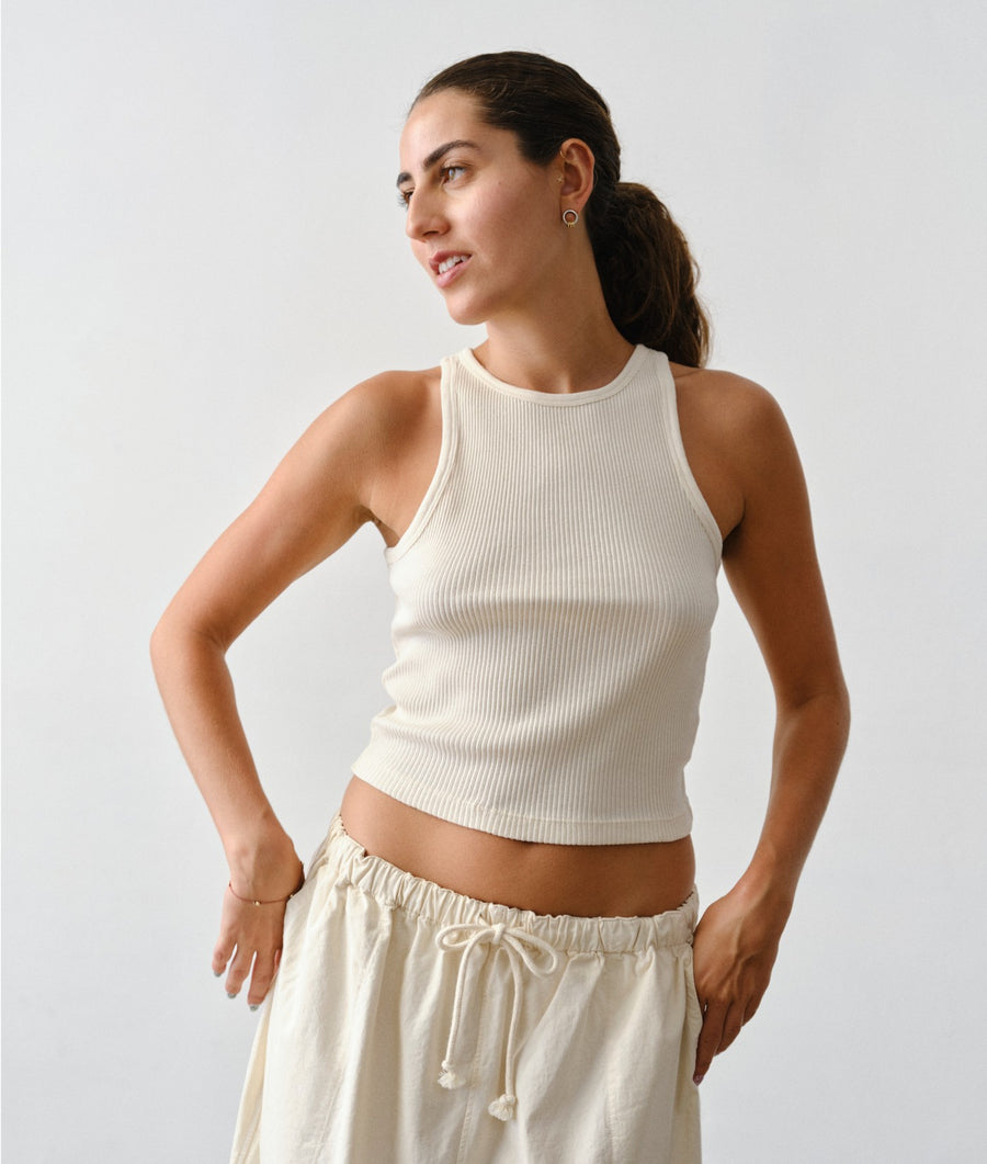 Woman wearing IOAN undyed Rib Tank against a solid gray background.