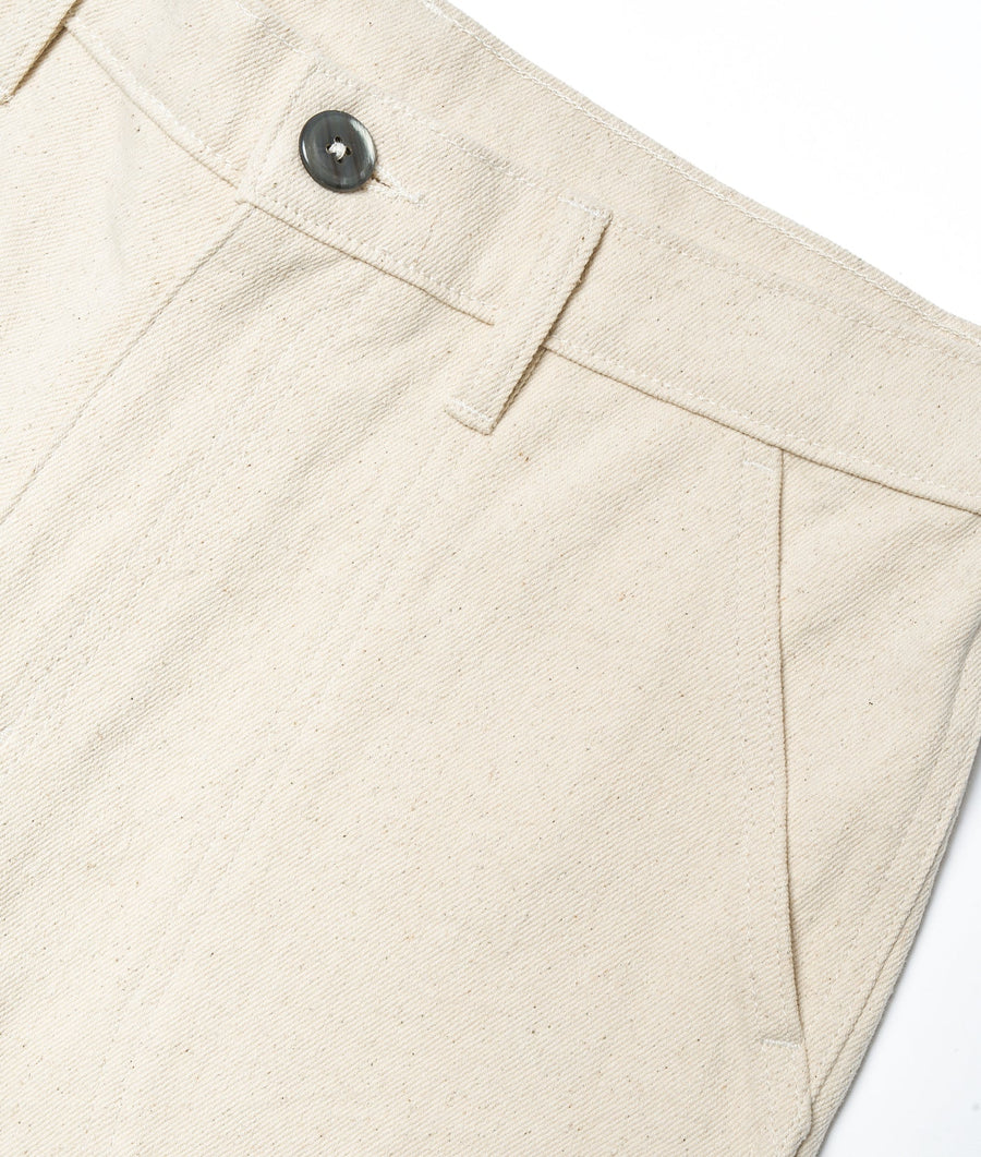 Detail shot of off-white linen pants with a black button closure - Industry of All Nations