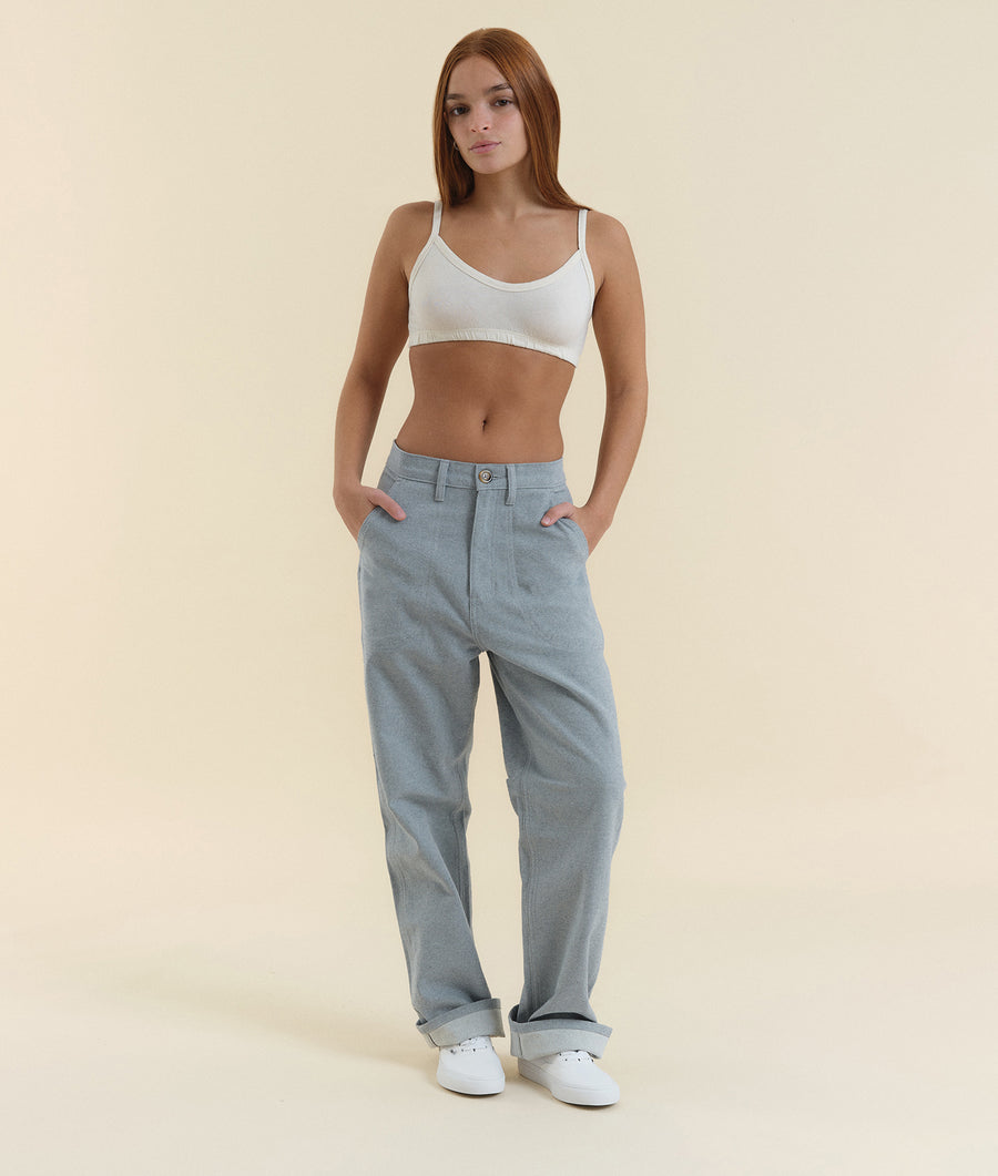A white cropped tank top and grey high-waisted pants worn by a young woman with long brown hair - Industry of All Nations