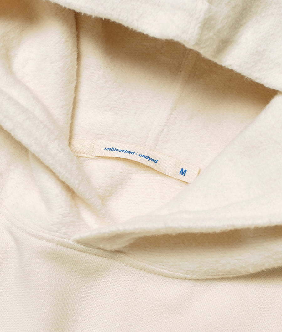 Closeup of a light tan-colored, unbleached and undyed cotton clothing item displaying a size tag - Industry of All Nations