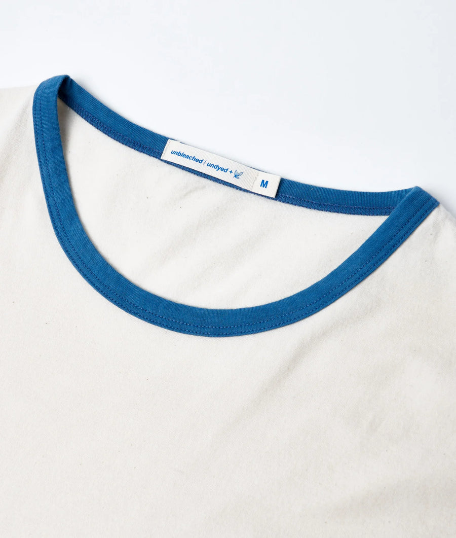 Flat lay image of a medium-sized white t-shirt with a blue, ribbed neckline and "unbleached/undyed" label - Industry of All Nations