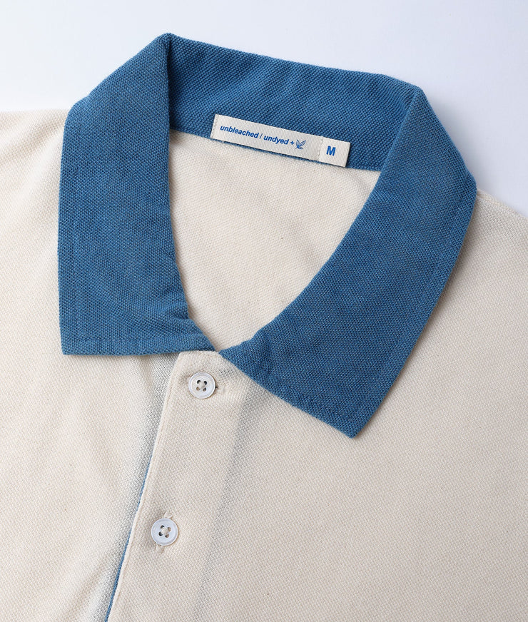 A detail shot of a navy blue and white pique cotton polo shirt on a light background - Industry of All Nations