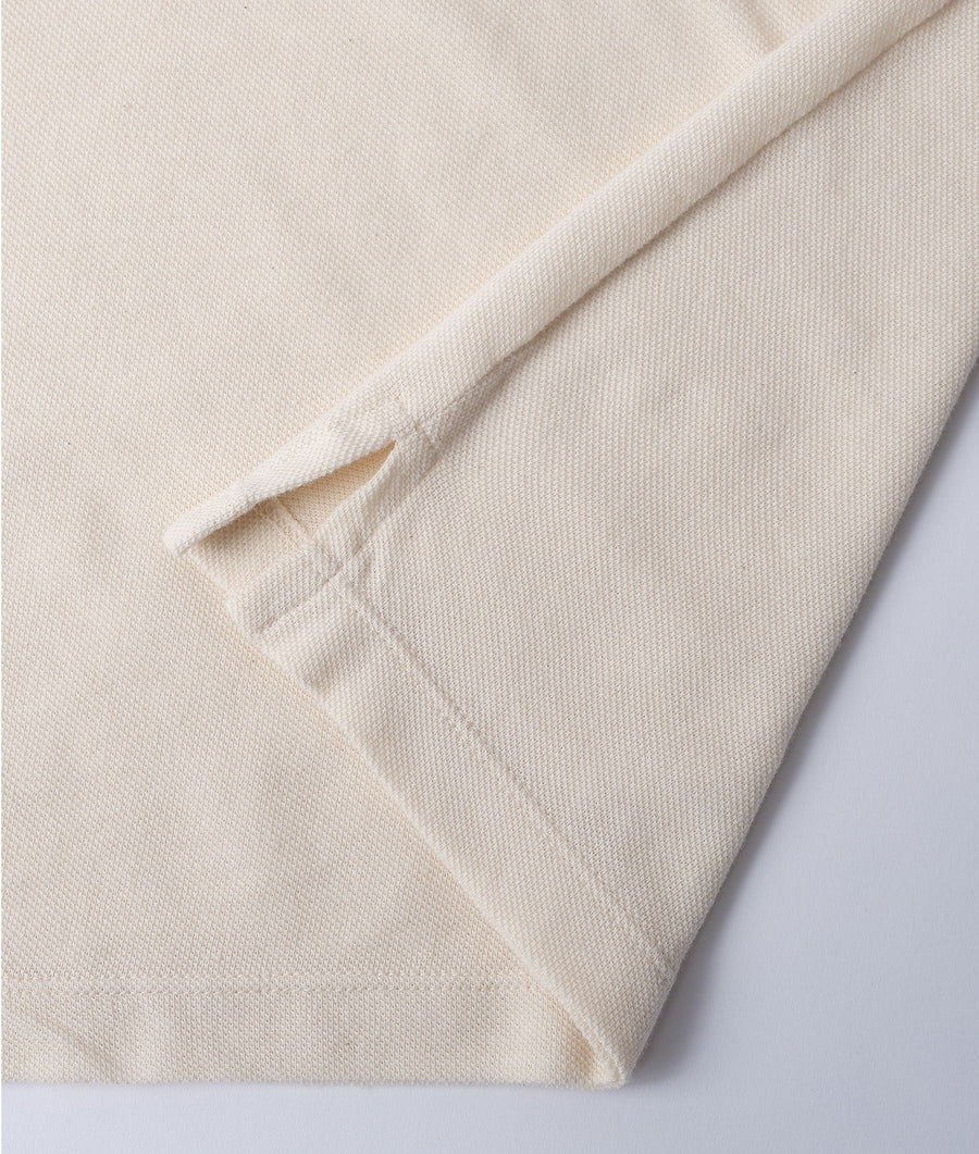 A close-up detail shot of a cream-colored, ribbed cotton knit fabric with an exposed seam detail - Industry of All Nations