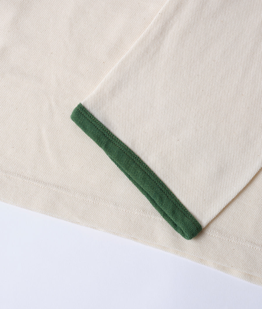 Close-up detail shot of a green knit cuff on a white cotton garment - Industry of All Nations